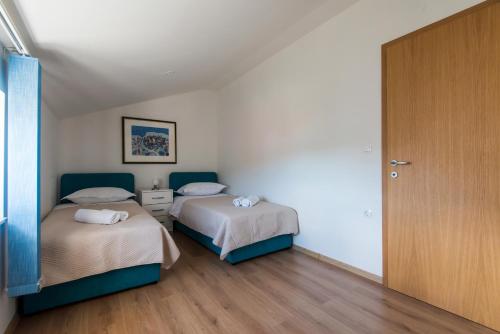 sypialnia z 2 łóżkami i drewnianą podłogą w obiekcie Apartments Vidov by the beach w mieście Kali