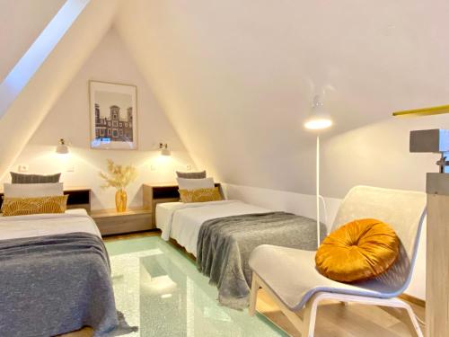 a attic bedroom with two beds and a chair at Wroclaw Inn Apartments in Wrocław