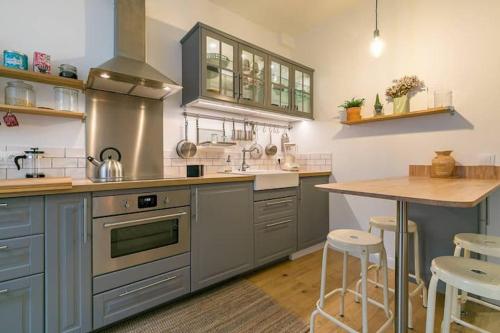 une cuisine avec des placards gris et un comptoir en bois dans l'établissement le Tillot, à Dijon