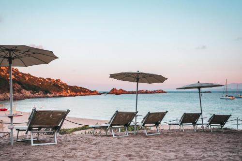 a group of chairs and umbrellas on a beach at Hotel Moresco in Santa Teresa Gallura