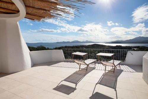 a patio with two chairs and tables on a balcony at Le Case Di Capriccioli in Porto Cervo