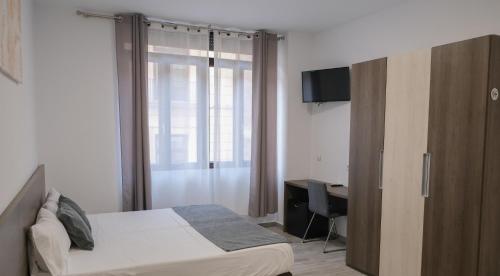 a bedroom with a bed and a desk with a television at Hostal Tartessos in Valencia