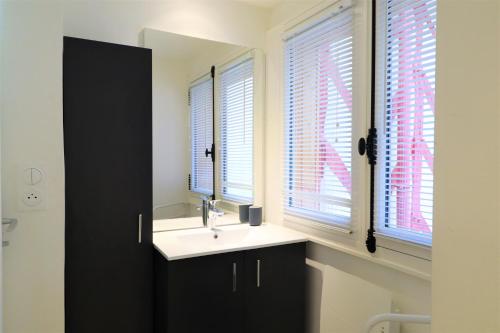 une salle de bain avec un lavabo et deux fenêtres dans l'établissement Studio SAINT-VINCENT 150M DU PORT, à Vannes