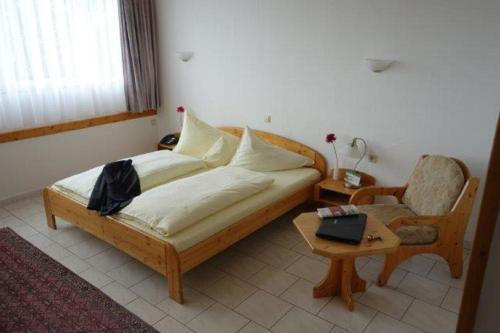 Eichenhof Hotel GbR في آيسلينغن: غرفة نوم بسرير وكرسي وطاولة