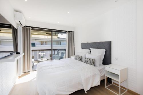 une chambre blanche avec un grand lit et une fenêtre dans l'établissement Carlton area XXL luxe 1 bed with large terrace, à Cannes