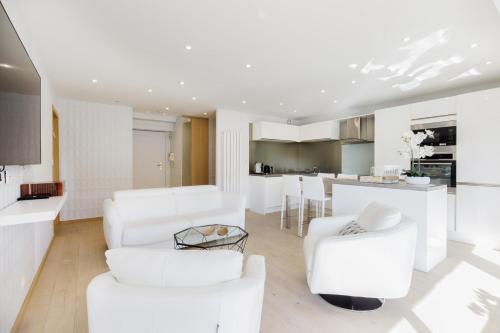 Il comprend un salon blanc avec des chaises blanches et une cuisine. dans l'établissement Carlton area XXL luxe 1 bed with large terrace, à Cannes