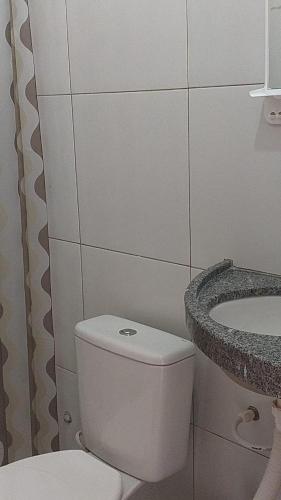 a white bathroom with a toilet and a sink at Pousada Jatobá in Barreirinhas