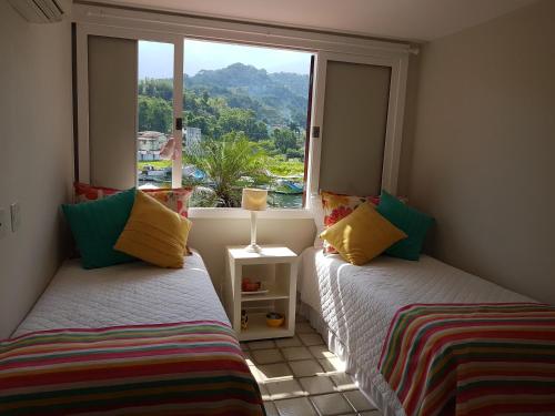 two beds sitting in a room with a window at Casa no Condomínio Porto Frade - pertinho da praia in Angra dos Reis
