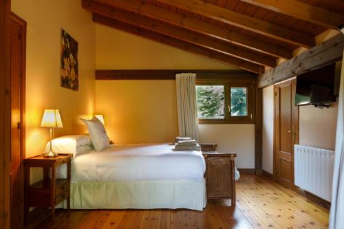 Un dormitorio con una cama blanca y una ventana. en Finca La Peñiga, en Mazcuerras