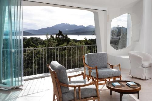 a room with two chairs and a balcony with a view at Le Case Di Capriccioli in Porto Cervo