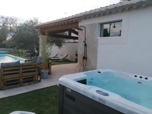 a hot tub in a yard next to a pool at L'atelier de Guytou et Spa in Cheval-Blanc