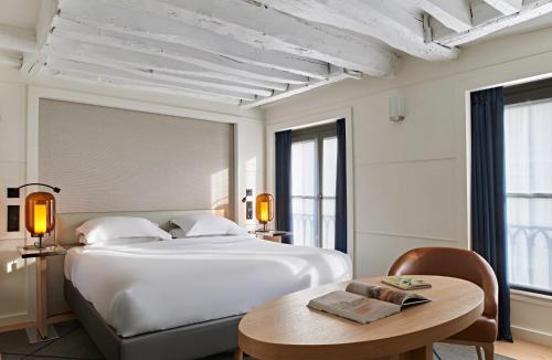 um quarto com uma grande cama branca e uma mesa em Hotel Opéra Richepanse em Paris