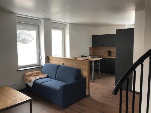 un salon avec un canapé bleu et une cuisine dans l'établissement Le Duplex, à Gérardmer
