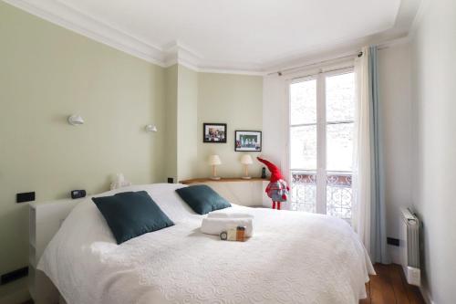 une chambre avec un grand lit blanc et une fenêtre dans l'établissement Appartement Duhesme - Welkeys, à Paris