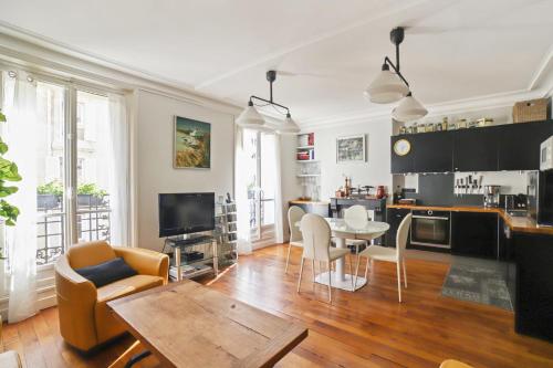 un salon avec une table et des chaises et une cuisine dans l'établissement Appartement Duhesme - Welkeys, à Paris