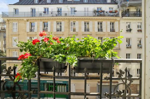 deux planteurs de fleurs rouges devant un bâtiment dans l'établissement Appartement Duhesme - Welkeys, à Paris