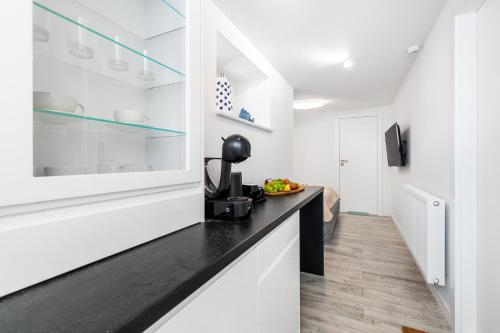 a kitchen with white cabinets and a black counter top at Sopot Pier Apartments by OneApartments in Sopot