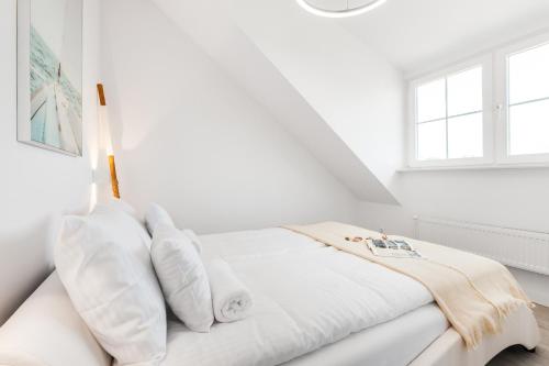 a white bedroom with a bed with white pillows at Sopot Pier Apartments by OneApartments in Sopot
