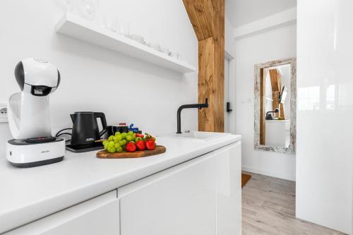 a kitchen with white cabinets and a counter top with fruit on it at Sopot Pier Apartments by OneApartments in Sopot