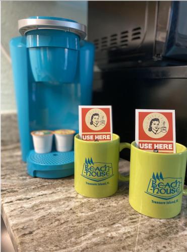 three coffee mugs sitting on a counter next to a coffee maker at The Beach House - Treasure Island in St Pete Beach