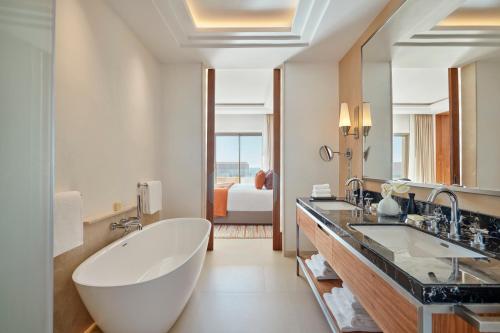 a bathroom with a large tub and two sinks at Fairmont Taghazout Bay in Taghazout
