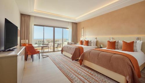 a hotel room with two beds and a flat screen tv at Fairmont Taghazout Bay in Taghazout