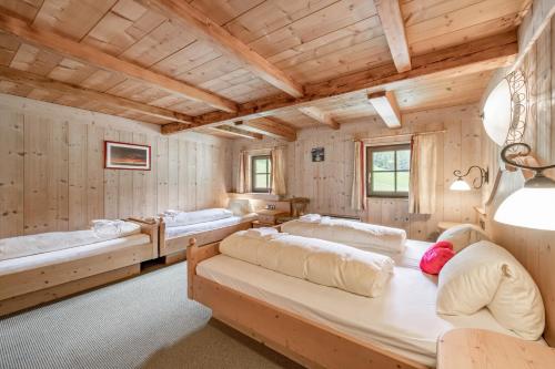 1 Schlafzimmer mit 3 Betten in einem Zimmer mit Holzwänden in der Unterkunft Landhaus im Grünen in Sölden