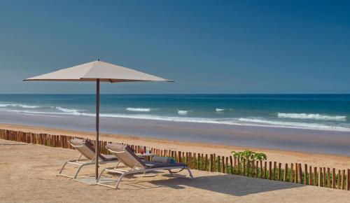 two chairs and an umbrella on a beach at Fairmont Taghazout Bay in Taghazout