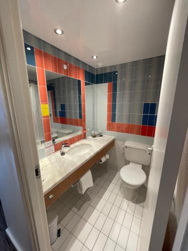 a bathroom with a toilet, sink, and mirror at Copthorne Manchester Salford Quays in Manchester