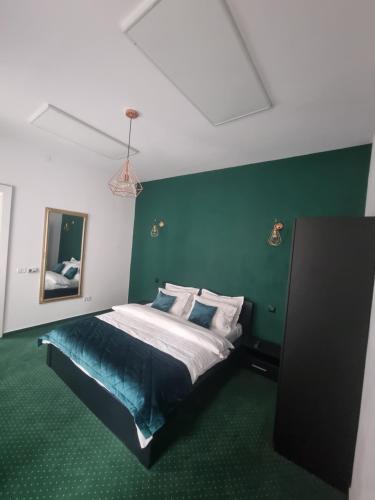 a bedroom with a bed with a green wall at Celebrity Apartment Brasov in Braşov