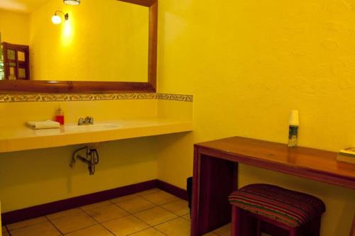 a yellow bathroom with a sink and a mirror at Hotel Jaguar Inn Tikal in Tikal