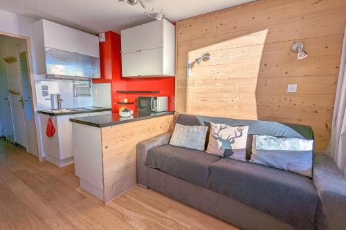 a living room with a couch and a kitchen at Cosy studio with balcony at the heart of L'Alpe d'Huez - Welkeys in LʼHuez