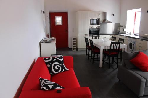 a living room with a red couch and a kitchen at Adega Do Mirante in São Roque do Pico