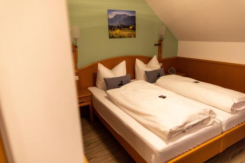 una camera da letto con un letto con lenzuola e cuscini bianchi di Gasthof Engel a Kaufbeuren