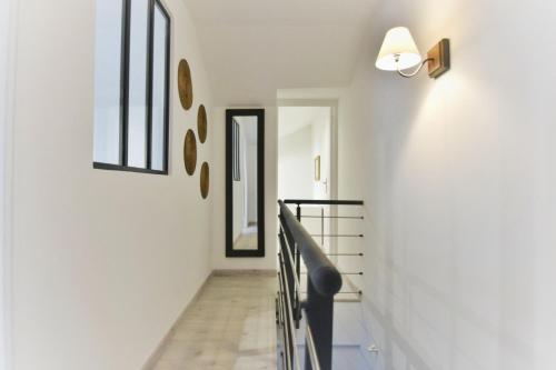 a hallway with white walls and a staircase with a mirror at Campagne en ville! in Compiègne