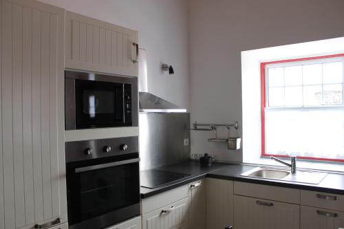 a kitchen with a stove and a sink and a microwave at Adega Do Mirante in São Roque do Pico