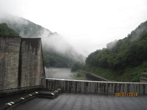 a view of a dam with a misty mountain at Hotel Le Commerce in Neuville