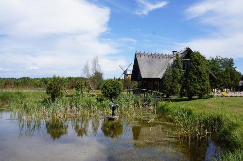 a man standing in a pond in front of a house at Mardi Farm Stay in Karala