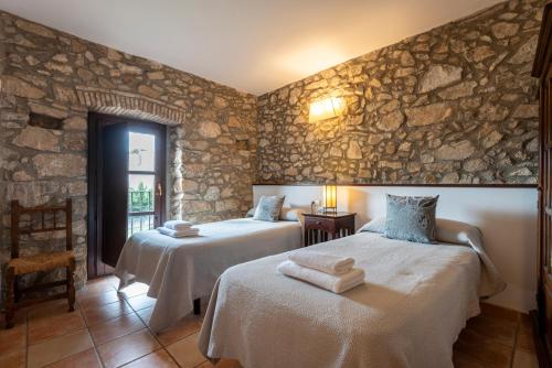 a bedroom with two beds and a stone wall at Can Llobet in Capmany