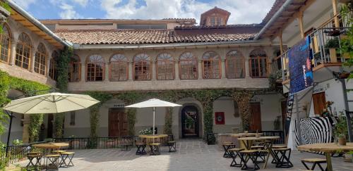 eine Außenterrasse mit Tischen und Sonnenschirmen in einem Gebäude in der Unterkunft Hommam in Cusco