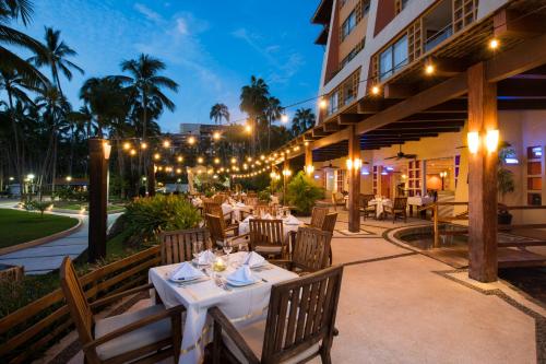 an outdoor restaurant with white tables and chairs at night at Club Regina Puerto Vallarta in Puerto Vallarta