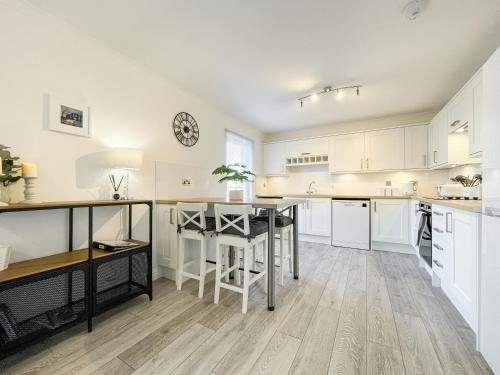 a large kitchen with white cabinets and a table at Pier View Apartment in Oban