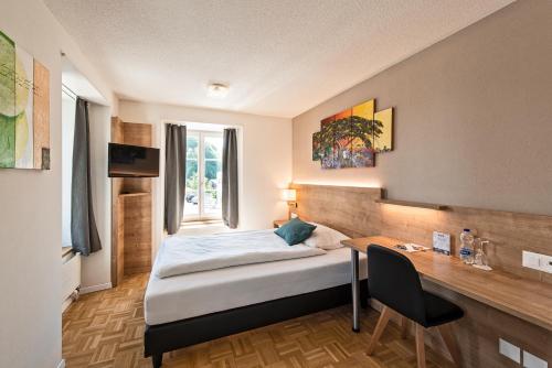 a hotel room with a bed and a desk and a window at Hotel zum Hirschen in Schindellegi