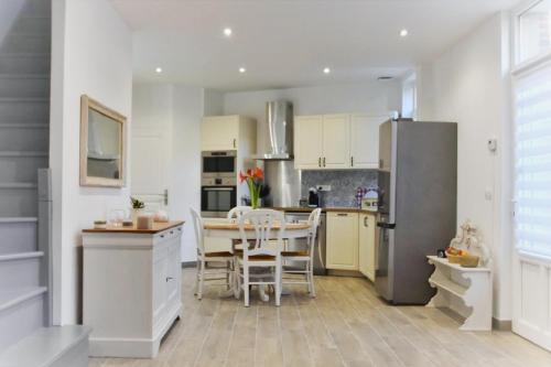 a kitchen with a table and a stainless steel refrigerator at Campagne en ville! in Compiègne