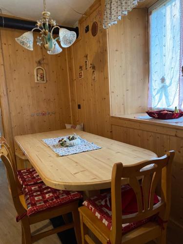un tavolo in legno con sedie in una stanza con finestra di Casa Mia Fiemme a Carano