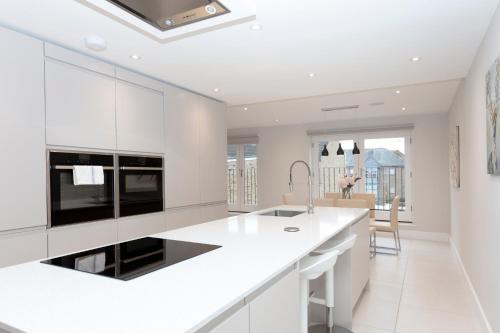 a white kitchen with a large white counter top at Stunning Central Windsor Town House With Parking in Windsor