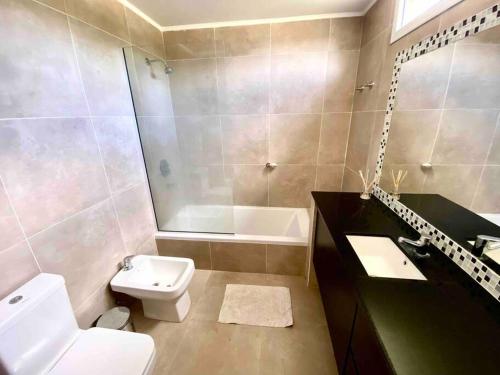 a bathroom with a toilet and a sink and a tub at Casa con pileta y parrilla en barrio privado, 2 dormitorios in General Roca