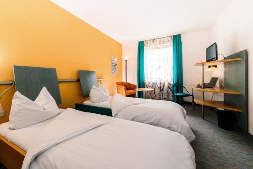 a hotel room with two beds and a desk at Hotel Residenz in Schnelldorf