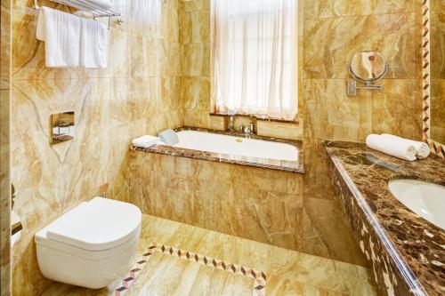 a bathroom with a toilet and a tub and a sink at Hotel Atlas Deluxe in Lviv