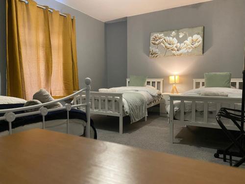 a living room with two beds and a table at 2 Bed Flat - Sleeps 6 - Pets - Parking - Wifi in Bridgend